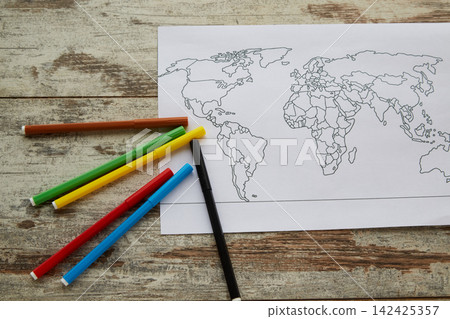 Black and white world map lies on wooden table with colorful markers. Black and white world map lies on wooden table with colorful markers. 142425357