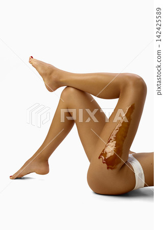 Raised female legs show wax layer during hair removal Raised female legs show wax layer during hair removal 142425589