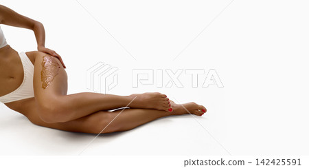 Woman lies on floor with wax applied along upper thigh Woman lies on floor with wax applied along upper thigh 142425591