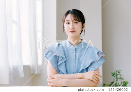 房間裡,一位年輕女子雙手交叉抱在胸前。 房間裡,一位年輕女子雙手交叉抱在胸前。 142426002