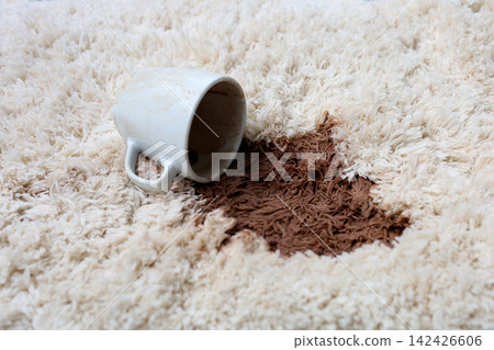 A white coffee mug creating a large brown stain on carpet. A white coffee mug creating a large brown stain on carpet. 142426606