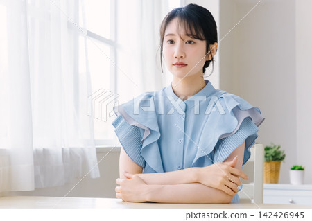 房間裡,一位年輕女子雙手交叉抱在胸前。 房間裡,一位年輕女子雙手交叉抱在胸前。 142426945