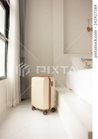 Suitcase Beside a Bed in a Bright Room in Chonburi, Thailand Suitcase Beside a Bed in a Bright Room in Chonburi, Thailand 142427164