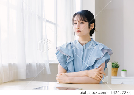 房間裡,一位年輕女子雙手交叉抱在胸前。 房間裡,一位年輕女子雙手交叉抱在胸前。 142427284