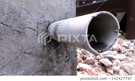 PVC drainage pipe protruding from the cracked concrete structure. 142427797