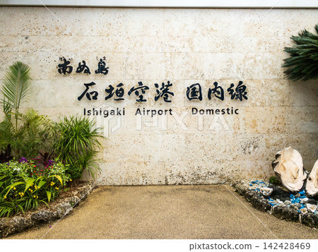 石垣機場(日本南部島嶼)的國內航班資訊指示牌和熱帶植物。 石垣機場(日本南部島嶼)的國內航班資訊指示牌和熱帶植物。 142428469