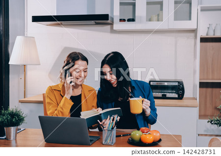 Portrait of military mother helping teen daughter with homework and eating lunch Portrait of military mother helping teen daughter with homework and eating lunch 142428731