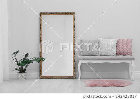 Modern large mirror and comfortable bench near light wall in room Modern large mirror and comfortable bench near light wall in room 142428817