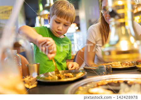 Family enjoying korean barbecue meal in restaurant 142428978
