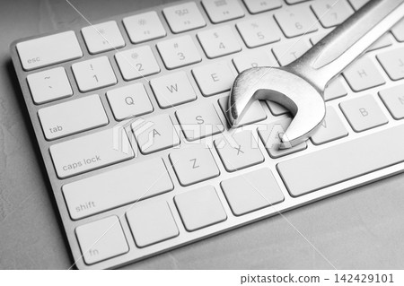 Keyboard and spanner on grey table, closeup. Concept of technical support 142429101