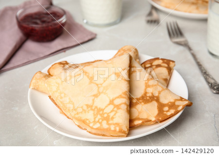 Folded fresh thin pancakes on light grey table Folded fresh thin pancakes on light grey table 142429120