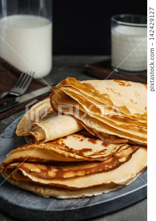 Fresh thin pancakes on grey board, closeup Fresh thin pancakes on grey board, closeup 142429127