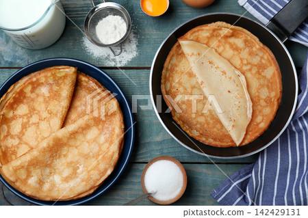 Flat lay composition with thin pancakes on blue wooden table Flat lay composition with thin pancakes on blue wooden table 142429131