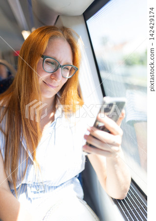 Woman traveling on train using mobile phone Woman traveling on train using mobile phone 142429174