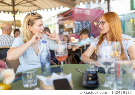 Women communicating using sign language at restaurant outdoors 142429183