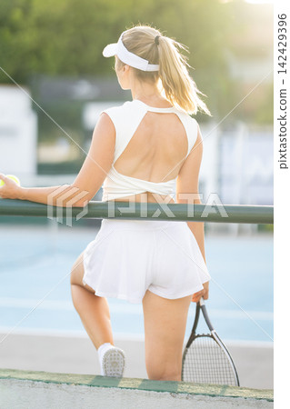 Woman tennis player standing on court holding racquet 142429396