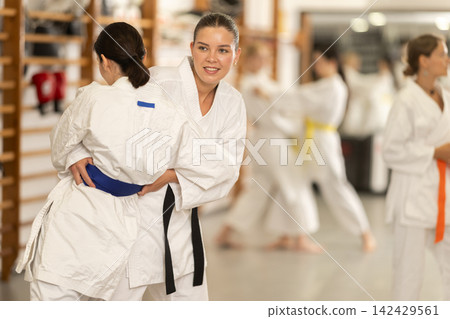 Women athletes in pair conduct training battle in oriental fighting technique judo Women athletes in pair conduct training battle in oriental fighting technique judo 142429561