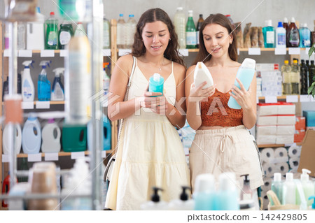 Young girls in summer clothes choosing shampoo in store Young girls in summer clothes choosing shampoo in store 142429805