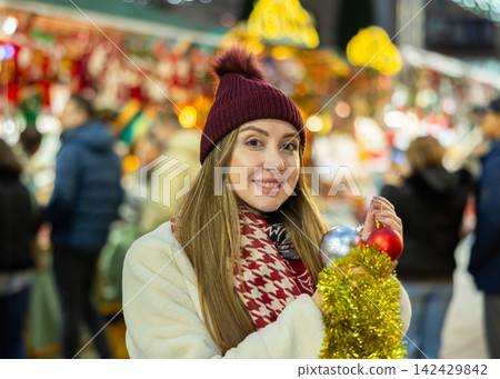 Young woman has purchased decorations for Christmas tree, tinsel and colorful balls Young woman has purchased decorations for Christmas tree, tinsel and colorful balls 142429842