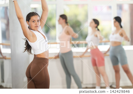 Warm-up sessions, young women doing ballet exercise standing in various ballet position in hall Warm-up sessions, young women doing ballet exercise standing in various ballet position in hall 142429846