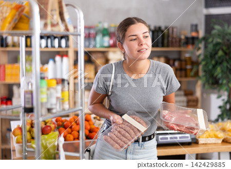 Woman choosing fresh meat in a hypermarket Woman choosing fresh meat in a hypermarket 142429885