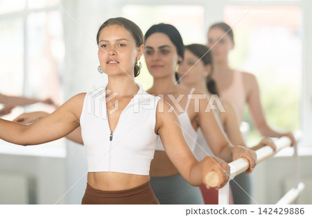 Young girl mastering second position at ballet barre in choreography studio Young girl mastering second position at ballet barre in choreography studio 142429886
