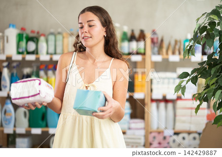 Young woman in summer clothes choosing feminine pads in retail store Young woman in summer clothes choosing feminine pads in retail store 142429887