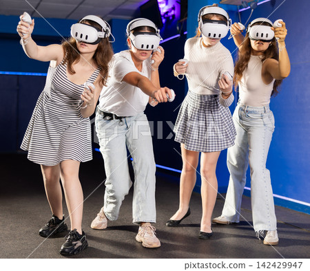 Young girls using virtual reality glasses - people having fun with new technology vr headset 142429947