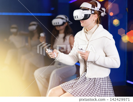 Young woman immersed in virtual reality game in gaming center Young woman immersed in virtual reality game in gaming center 142429971