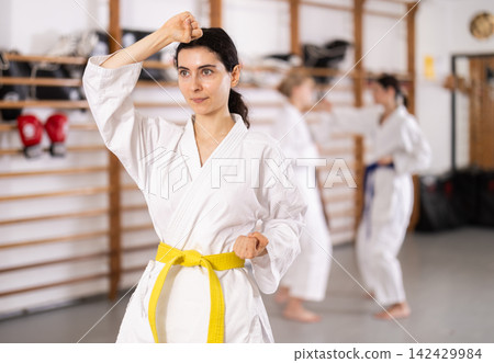 Willing young woman practicing kata in sports hall Willing young woman practicing kata in sports hall 142429984