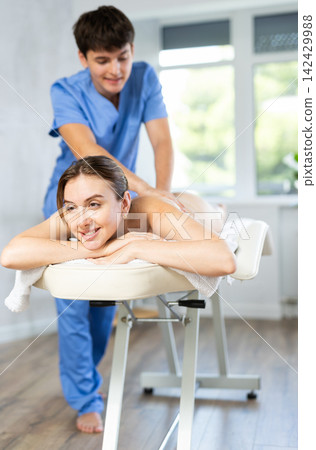 Young man massage therapist works with female client 142429988