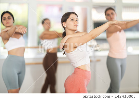 Adolescent girl mastering ballet moves at group class Adolescent girl mastering ballet moves at group class 142430005
