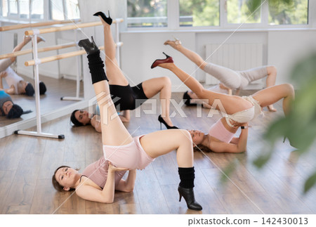 Female slender dancers in high heels and tight sexy clothes pose on floor Female slender dancers in high heels and tight sexy clothes pose on floor 142430013