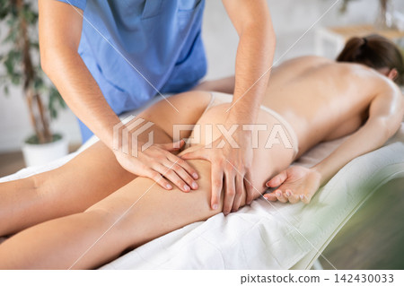 Hands of masseur performing leg massage for young female patient Hands of masseur performing leg massage for young female patient 142430033