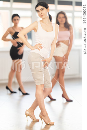 Graceful women blending sensuality with fashion while partaking in group high heels dance class Graceful women blending sensuality with fashion while partaking in group high heels dance class 142430081