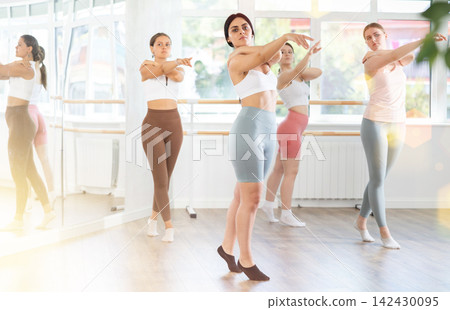 Young girl practicing ballet positions standing in row with others Young girl practicing ballet positions standing in row with others 142430095