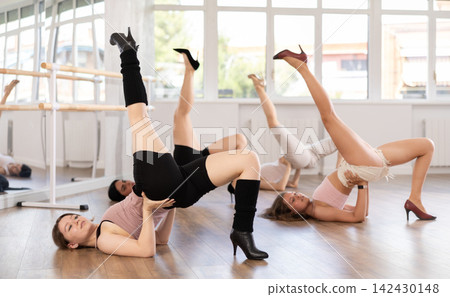Female slender dancers in high heels and tight sexy clothes pose on floor Female slender dancers in high heels and tight sexy clothes pose on floor 142430148