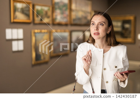 While visiting museum, girl uses travel guide application on her phone. While visiting museum, girl uses travel guide application on her phone. 142430187