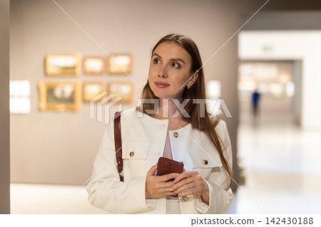 Woman with phone in museum Woman with phone in museum 142430188