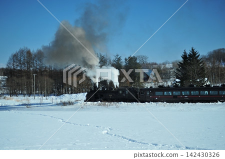 SL 冬季沼澤列車在北海道仙茂本線上的藍天下穿過廣闊的雪地。 SL 冬季沼澤列車在北海道仙茂本線上的藍天下穿過廣闊的雪地。 142430326