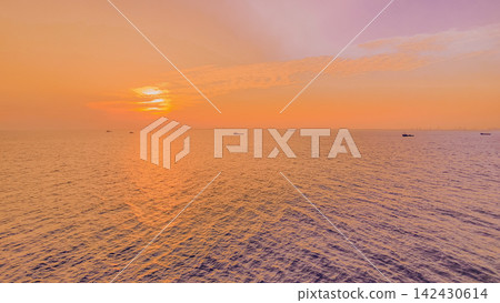 Tanker vessels on the ocean during a vibrant sunset, with the sun casting warm hues across the water and silhouettes of ships visible in the distance Tanker vessels on the ocean during a vibrant sunset, with the sun casting warm hues across the water and silhouettes of ships visible in the distance 142430614