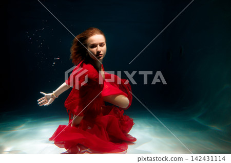 Vivid underwater image featuring glamorous red gown and expressive pose Vivid underwater image featuring glamorous red gown and expressive pose 142431114