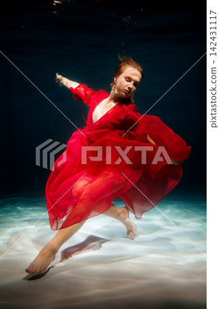 Model posed underwater wearing vibrant red clothing and flowing fabric Model posed underwater wearing vibrant red clothing and flowing fabric 142431117