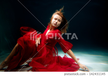Elegant dancer in scarlet costume maintains poised extension 142431145