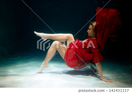 Caucasian dancer balancing in red costume in aquatic environment Caucasian dancer balancing in red costume in aquatic environment 142431157