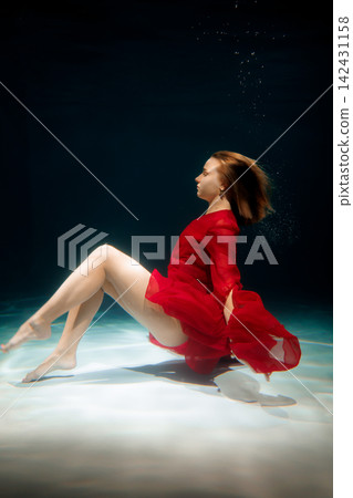 Dreamlike depiction of woman in flowing gown submerged in water 142431158