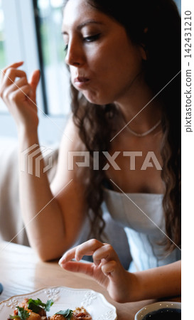 A beautiful girl eats food with her hands with gusto in a restaurant A beautiful girl eats food with her hands with gusto in a restaurant 142431210