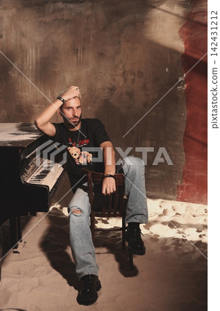 Casual male guitarist practicing amidst dim studio lighting and shadows Casual male guitarist practicing amidst dim studio lighting and shadows 142431212