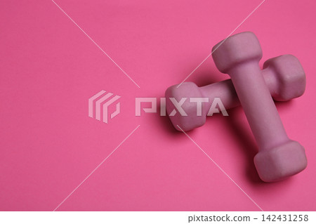 Modern dumbbells on pink background. Space for text Modern dumbbells on pink background. Space for text 142431258