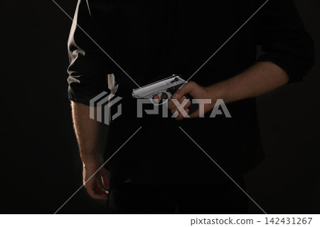 Professional killer with gun on black background, closeup Professional killer with gun on black background, closeup 142431267